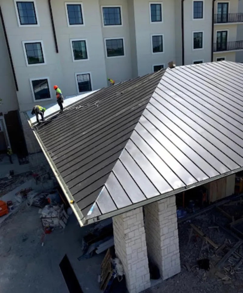 Crew installing standing seam metal roof panels on a commercial project in Chelmsford